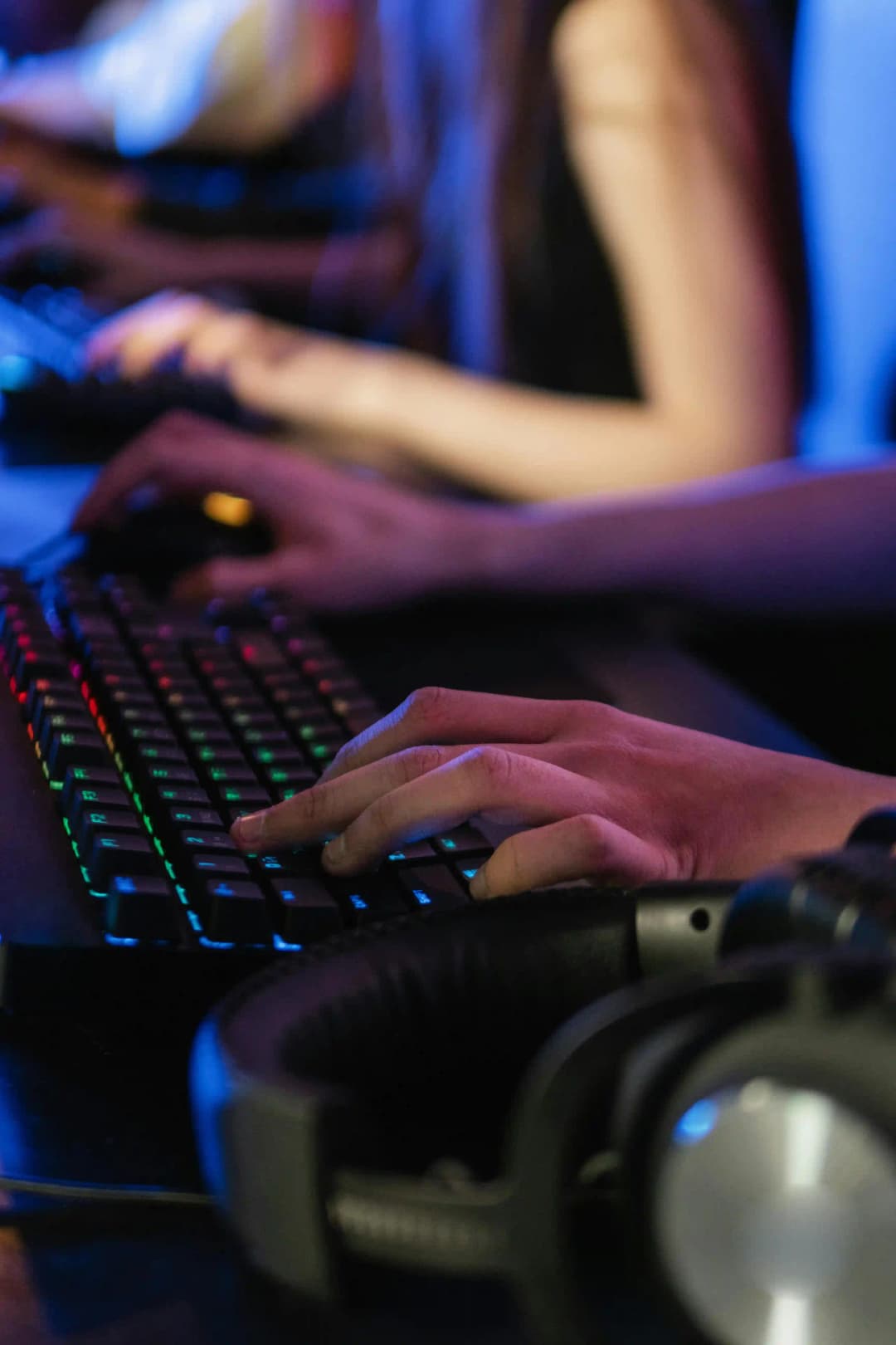Mains sur un clavier rétroéclairé en pleine session de jeu, dans une ambiance sombre typique des compétitions de jeux vidéo.